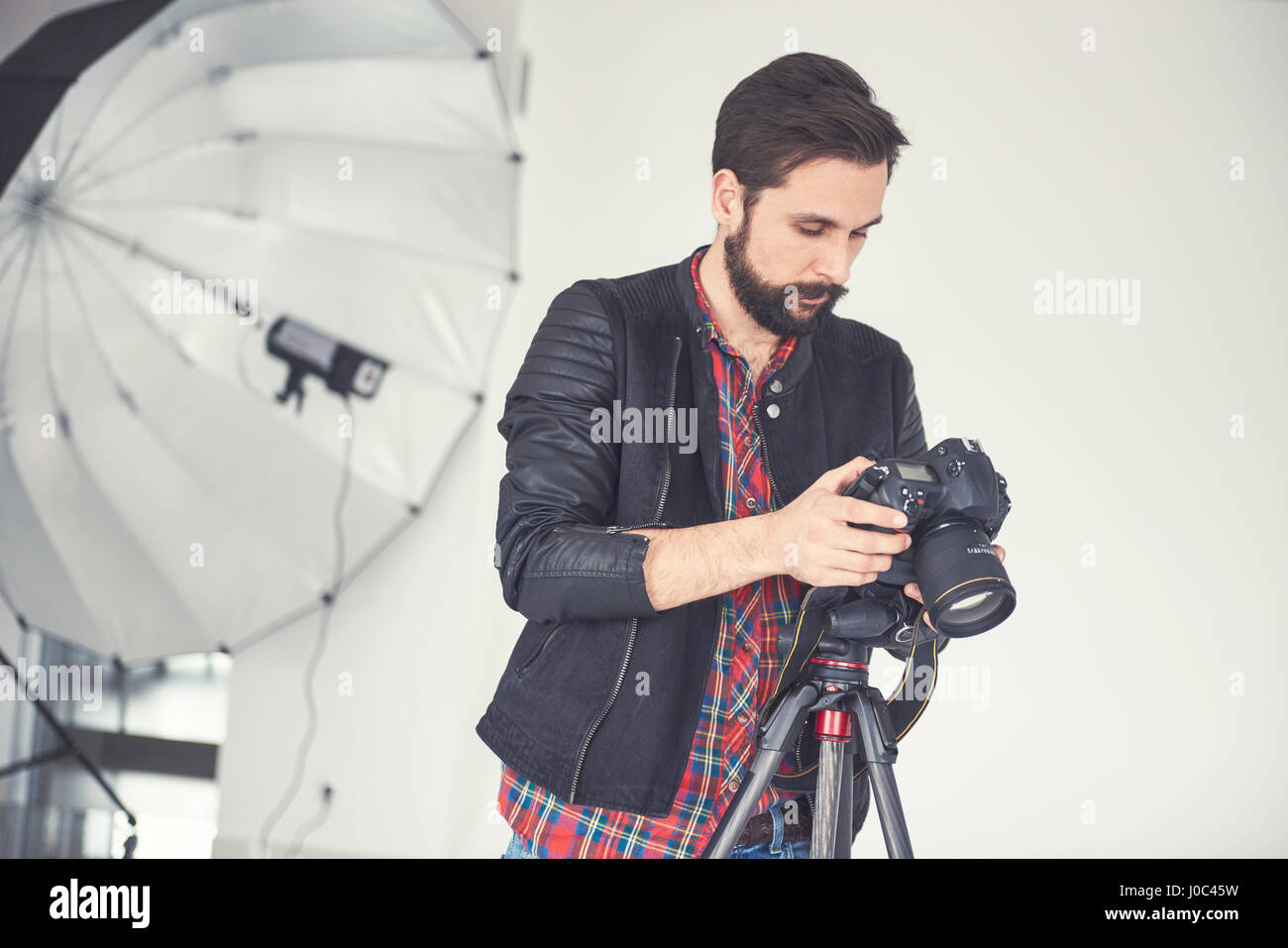 Fotografo maschio revisione di studio foto sulla fotocamera reflex digitale Foto Stock