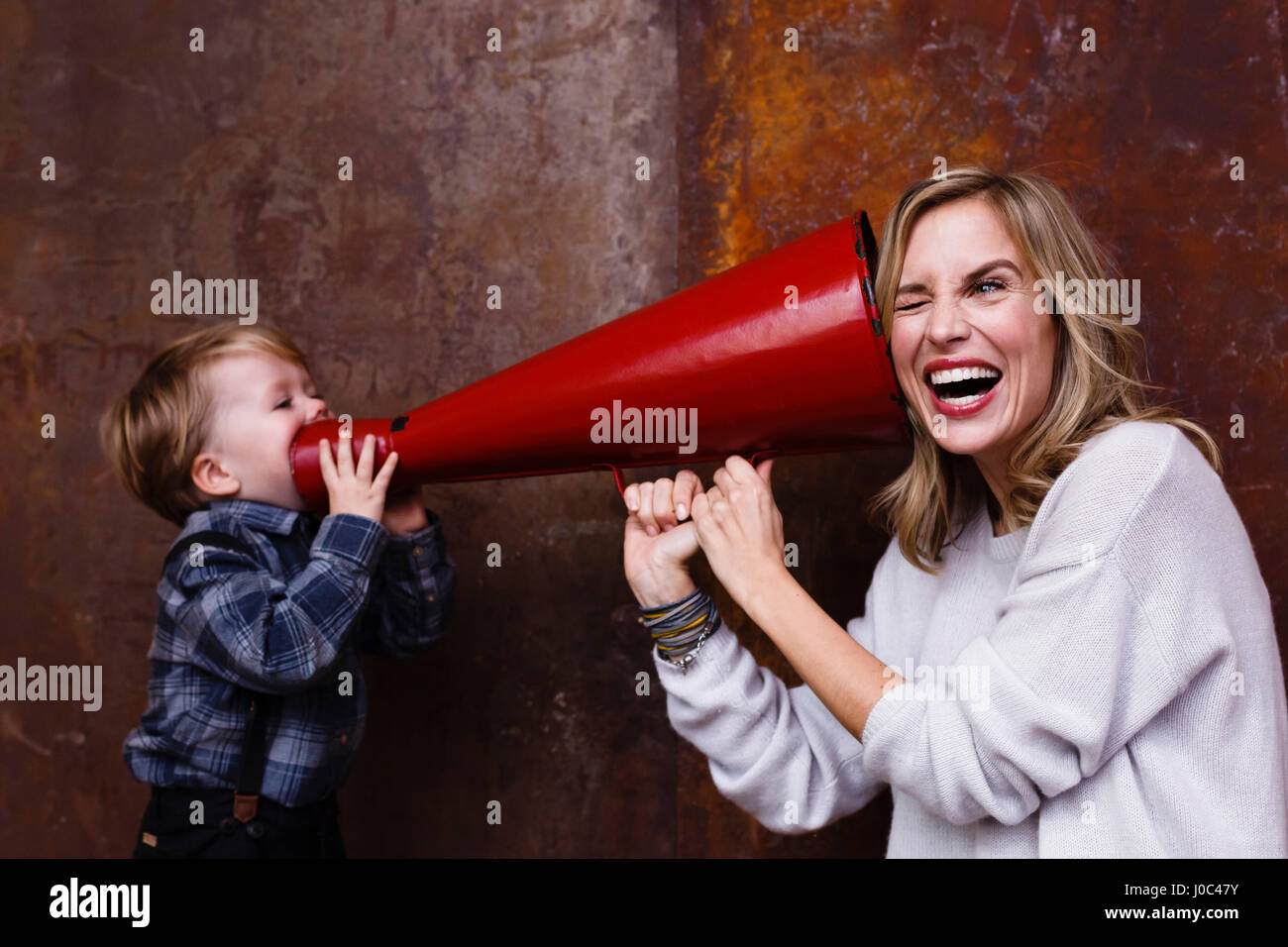 Giovane ragazzo parla nel megafono, donna holding megafono al suo orecchio Foto Stock