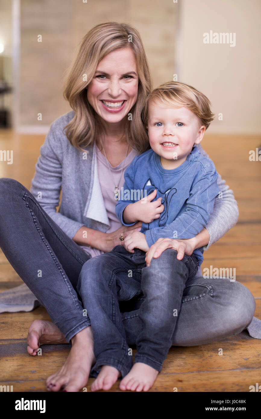 Ritratto di madre e figlio seduti sul pavimento, sorridente Foto Stock