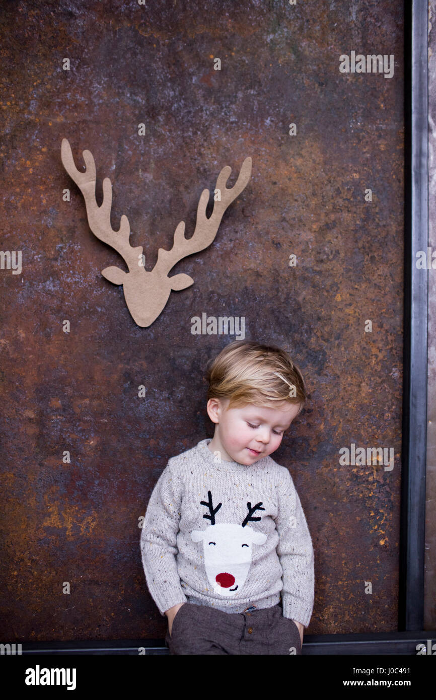 Ritratto di giovane ragazzo, renne di cartone ritagliati sulla parete dietro di lui Foto Stock