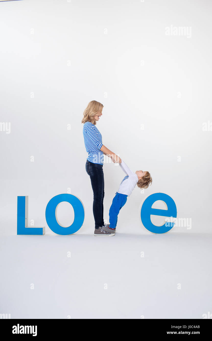 Madre e figlio tenendo le mani, piedi tra tridimensionale di lettere, creando la parola AMORE Foto Stock