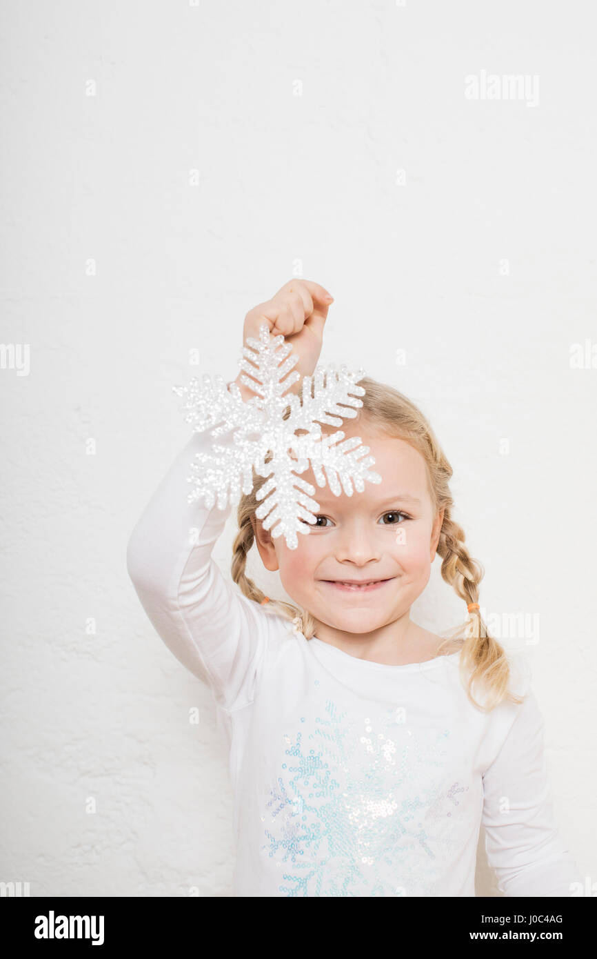 Ritratto di giovane ragazza contro uno sfondo bianco, tenendo il simbolo del fiocco di neve Foto Stock