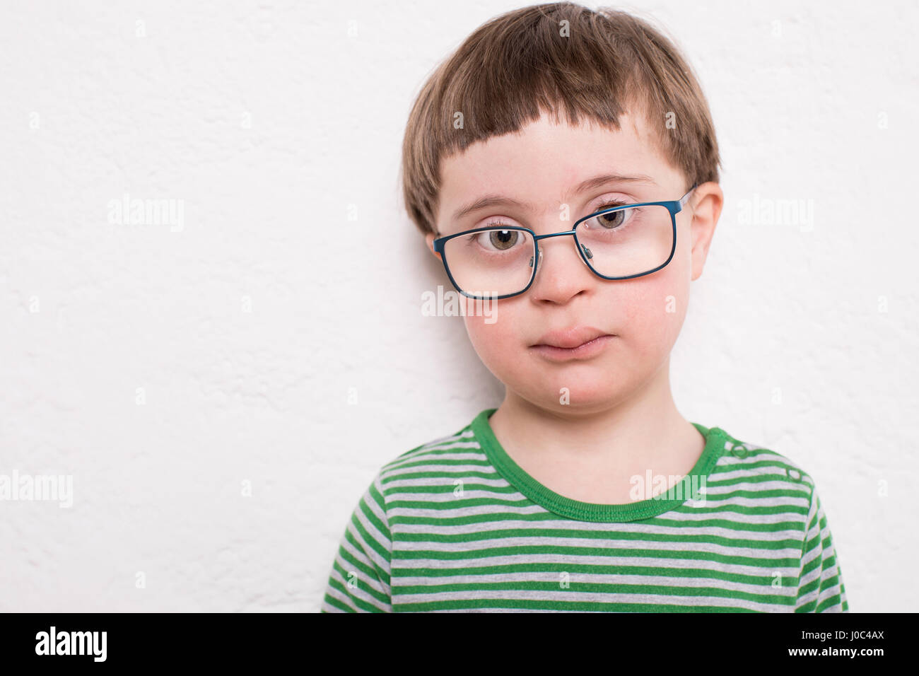 Ritratto di giovane ragazzo con gli occhiali, contro uno sfondo bianco Foto Stock