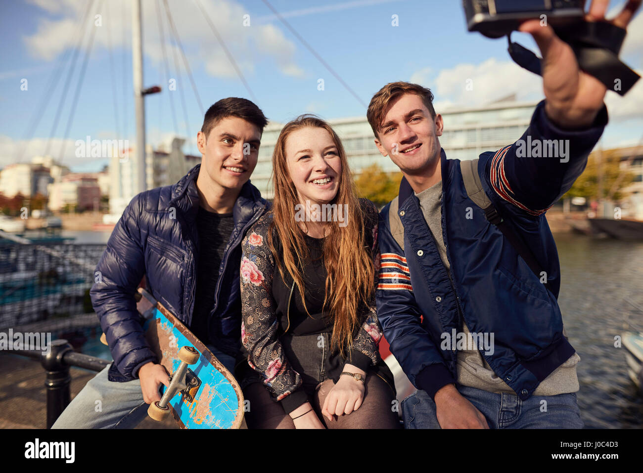 Tre amici seduti all'aperto, tenendo selfie con fotocamera, Bristol, Regno Unito Foto Stock
