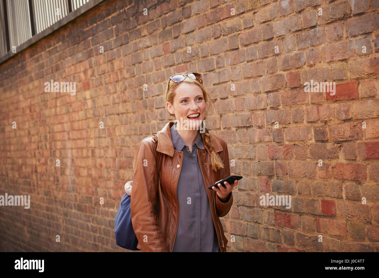 Donna che cammina lungo il muro di mattoni, London, Regno Unito Foto Stock