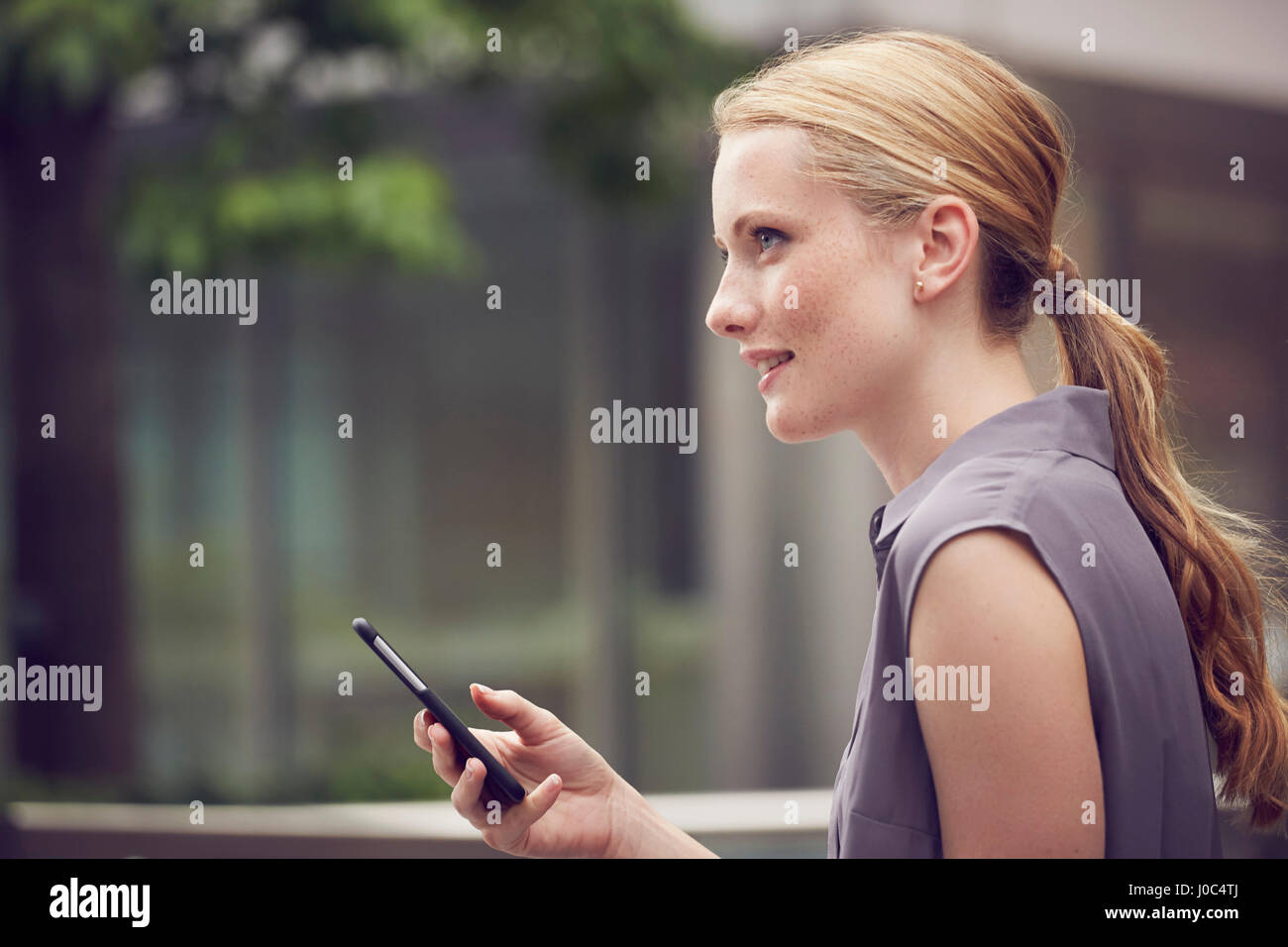 Donna che utilizza un cellulare in Street, Londra, Regno Unito Foto Stock