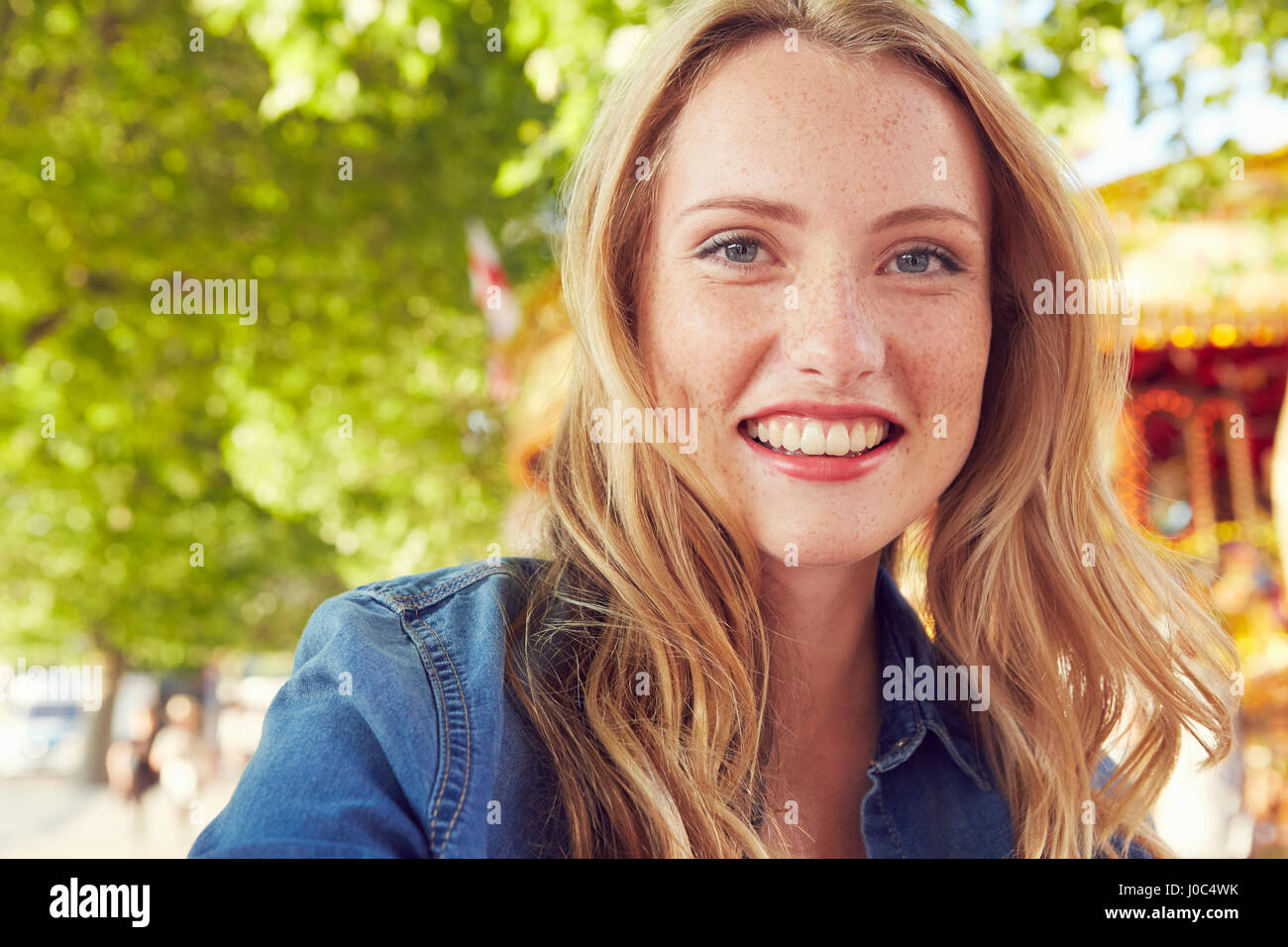 Donna sorridente, giostra in background, London, Regno Unito Foto Stock
