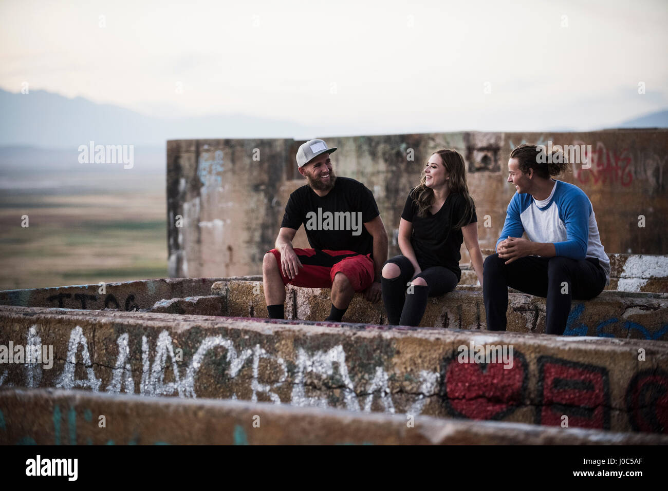 Giovani uomini e donne seduti sul muro di graffiti a ha rovinato il mio Foto Stock