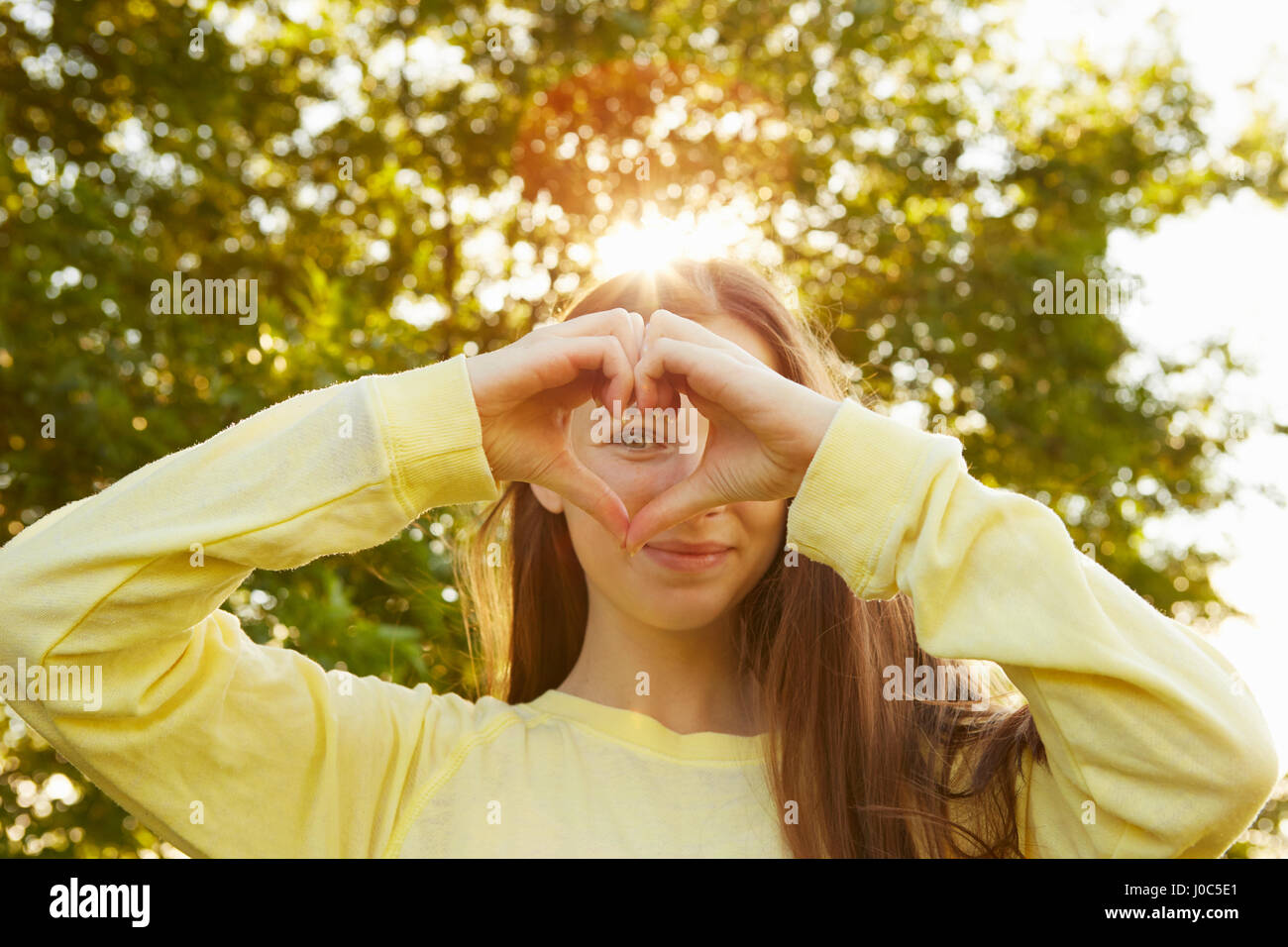 Ritratto di ragazza messa a forma di cuore con le mani in posizione di parcheggio Foto Stock