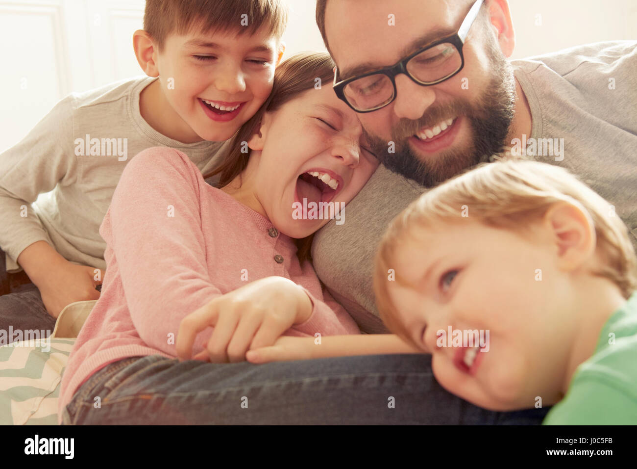 Padre e tre bambini ridere insieme Foto Stock