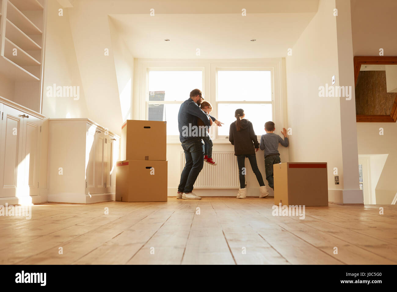Metà uomo adulti e tre bambini guardando dalla finestra della nuova casa Foto Stock