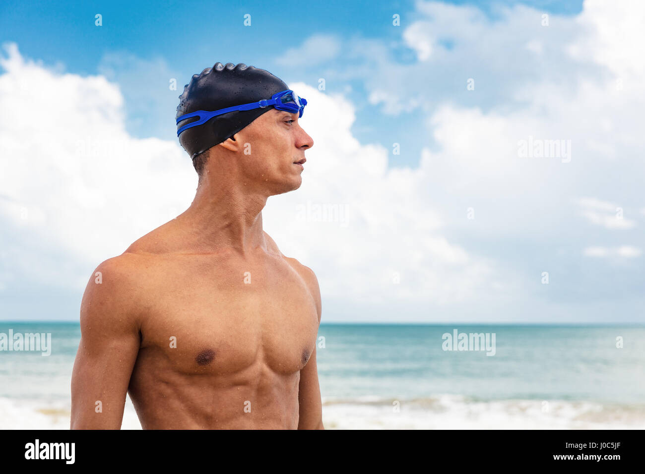 Maschio muscolare nuotatore sulla spiaggia che guarda lontano Foto Stock