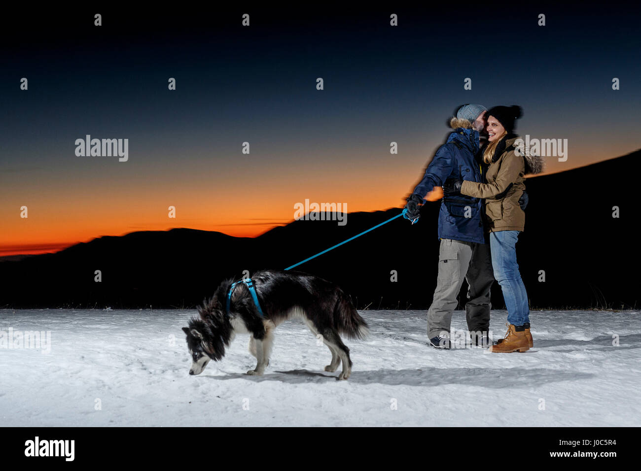 Coppia romantica con il cane nella neve durante la notte Foto Stock