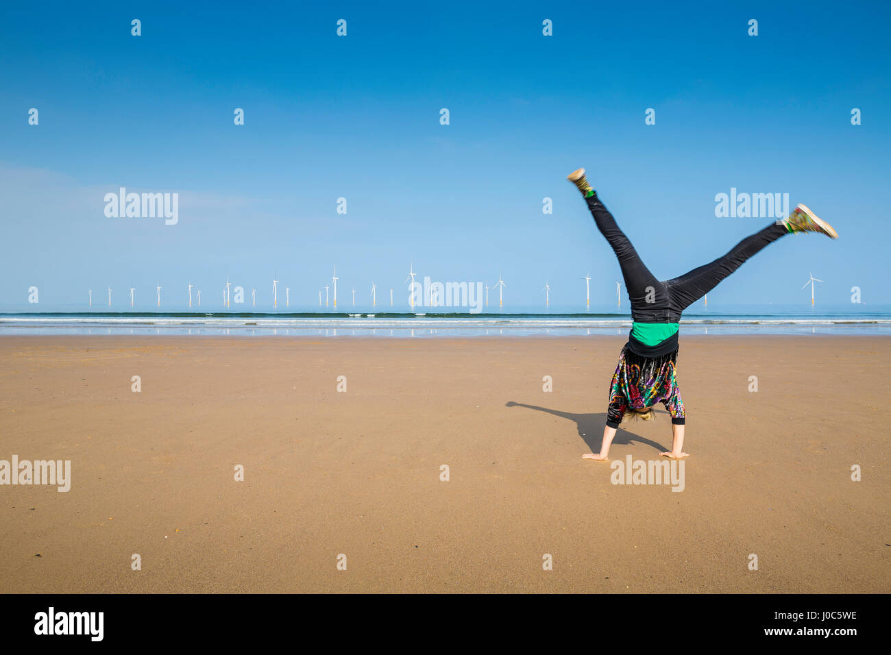 Donna matura facendo appoggiate su Redcar Beach, North Yorkshire, Regno Unito Foto Stock