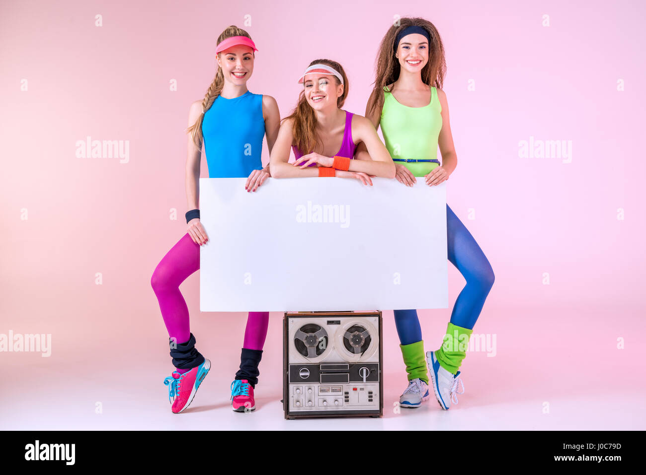 Sorridenti donne sportive azienda banner sul retro record giocatore in rosa Foto Stock