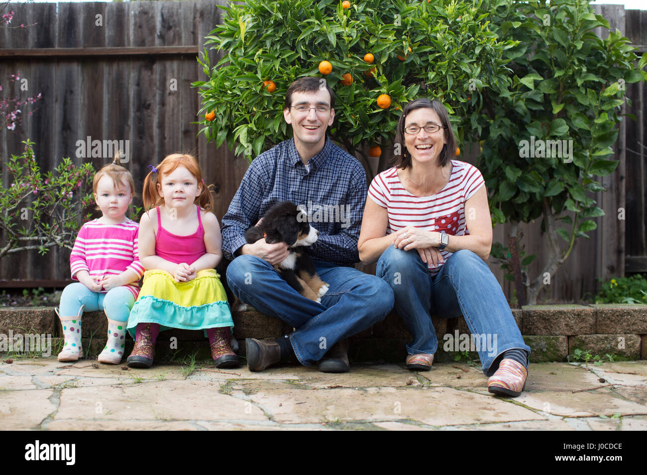Ritratto di giovane famiglia con cane, seduti in giardino Foto Stock