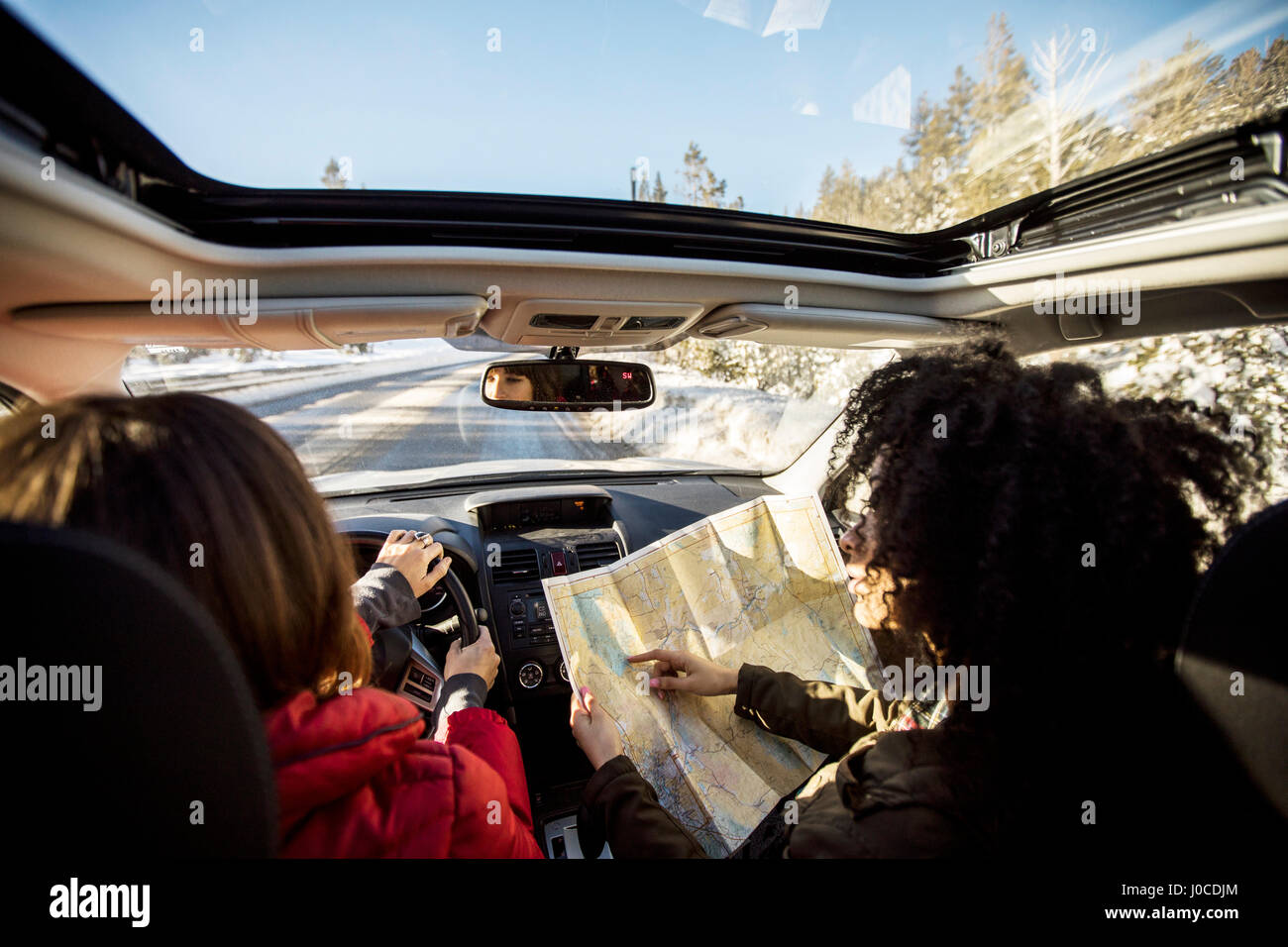 Donna alla guida di auto, amico nel sedile del passeggero guardando alla mappa Foto Stock