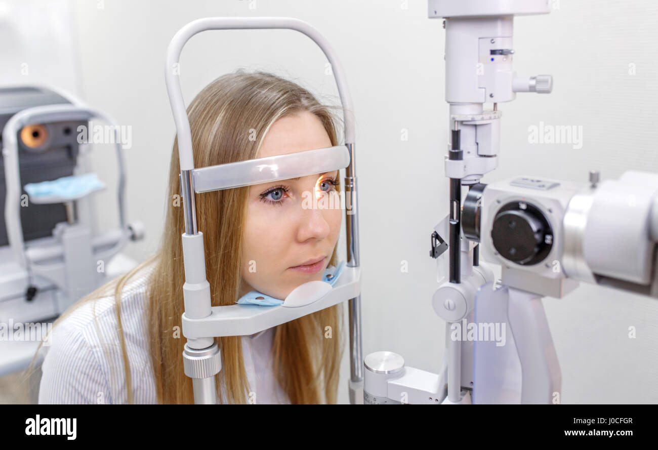 Piuttosto giovane donna con il suo occhi esaminati da un occhio medico di una lampada a fenditura Foto Stock