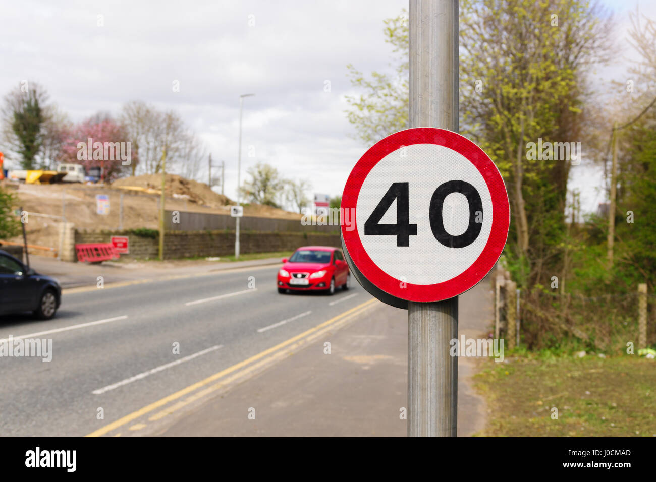 Urban 40 miglia per ora il limite massimo di velocità segno utilizzato nel Regno Unito con defocussed traffico in background Foto Stock