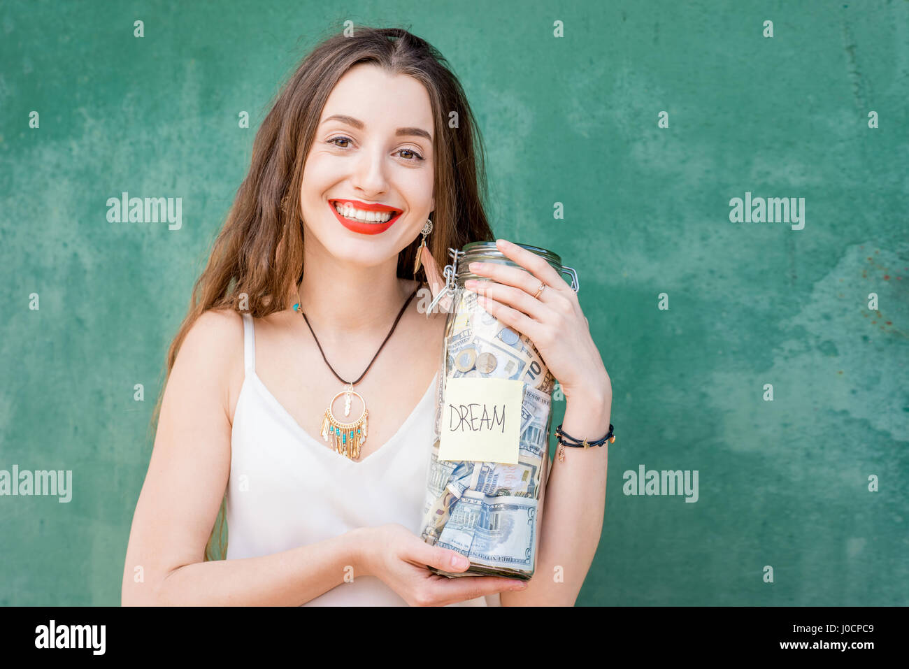 Donna che mantiene un flacone pieno di risparmio di denaro Foto Stock