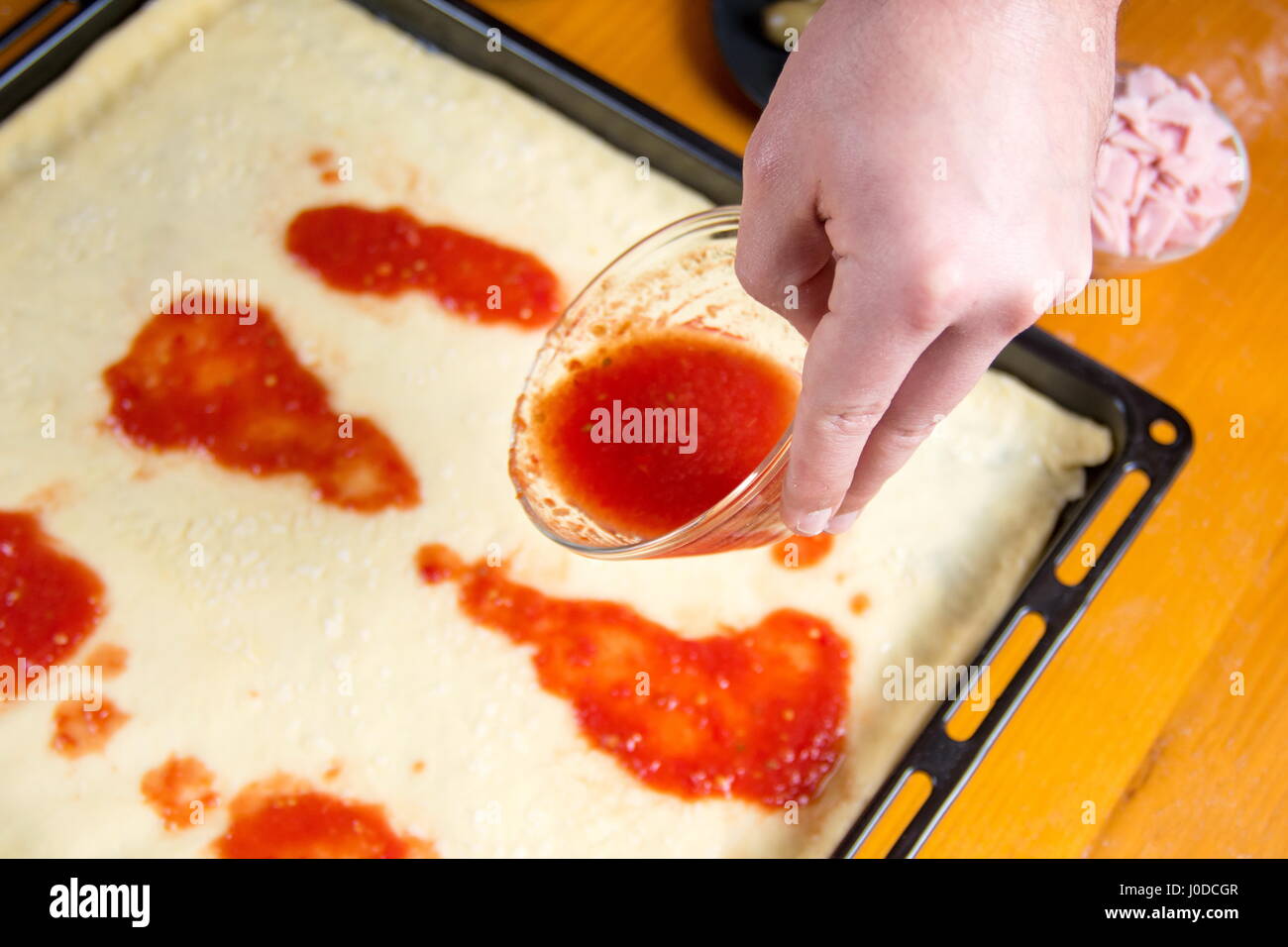 Uomo di mettere la salsa di pomodoro sulle materie di base per pizza Foto Stock
