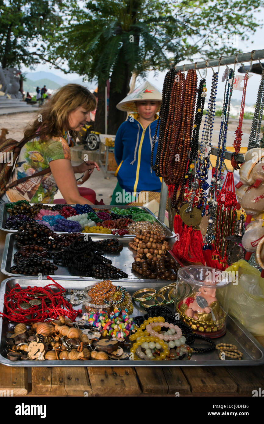 Vista verticale di una signora di vendita gioielli per un turista da un mercato in stallo in Vietnam Foto Stock