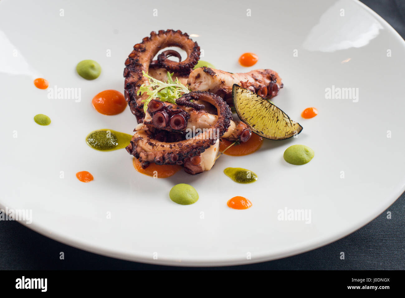 Polpo Alla Griglia Tagliata Con Un Coltello Per Il Cibo Su Una Piastra Bianca Foto Stock Alamy