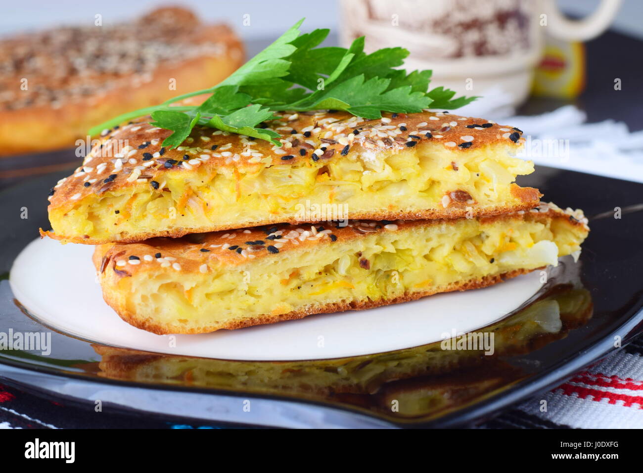 Due pezzi di cavolo bianco con torta di carote su una piastra nera con tazza di tè e il resto della torta su un sfondo di materie tessili. Una sana prima colazione. Supporto semplice. Mangiare sano concetto. Foto Stock