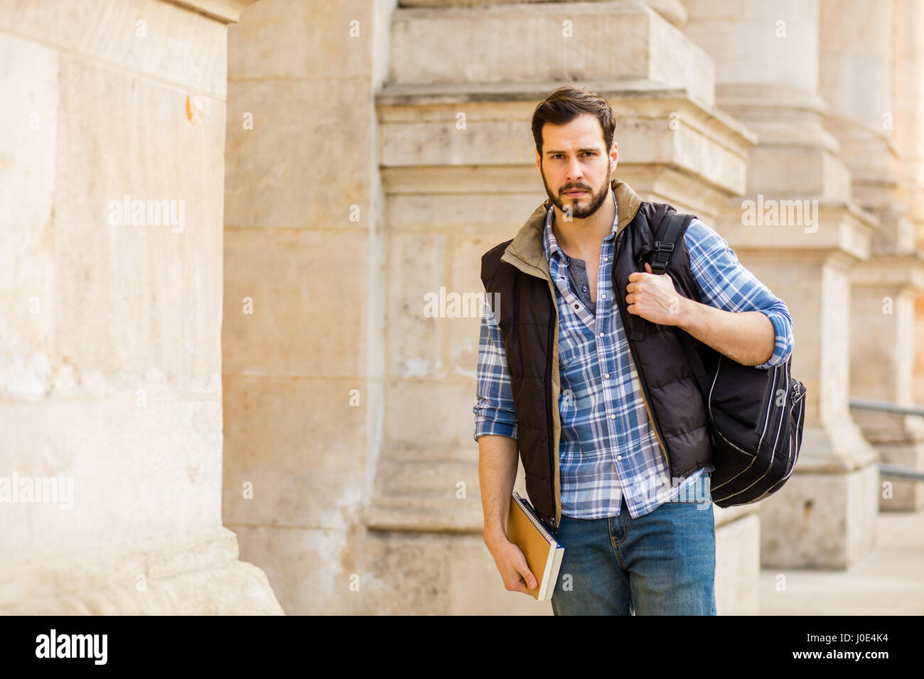 Giovane uomo bello, studente a fronte di una università con zaino e libri Foto Stock