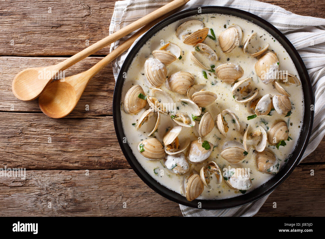 Delicatessen cibo: vongole stufati in crema con aglio e verdi di close-up su una piastra su un tavolo. vista orizzontale dal di sopra Foto Stock
