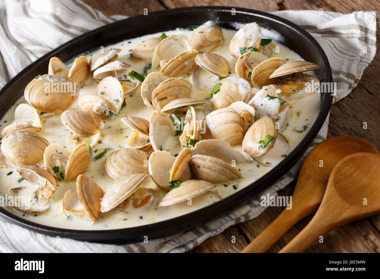 Delicatessen cibo: vongole stufati in crema con aglio e verdi di close-up su una piastra su un piano orizzontale. Foto Stock