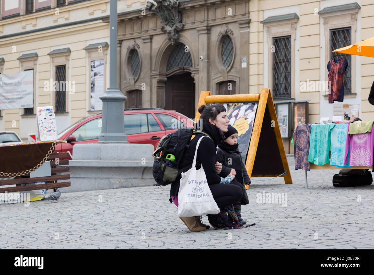 Unico giovane madre con bambino figlia ascoltare musicista di strada sul mercato di Brno, Cechia Foto Stock