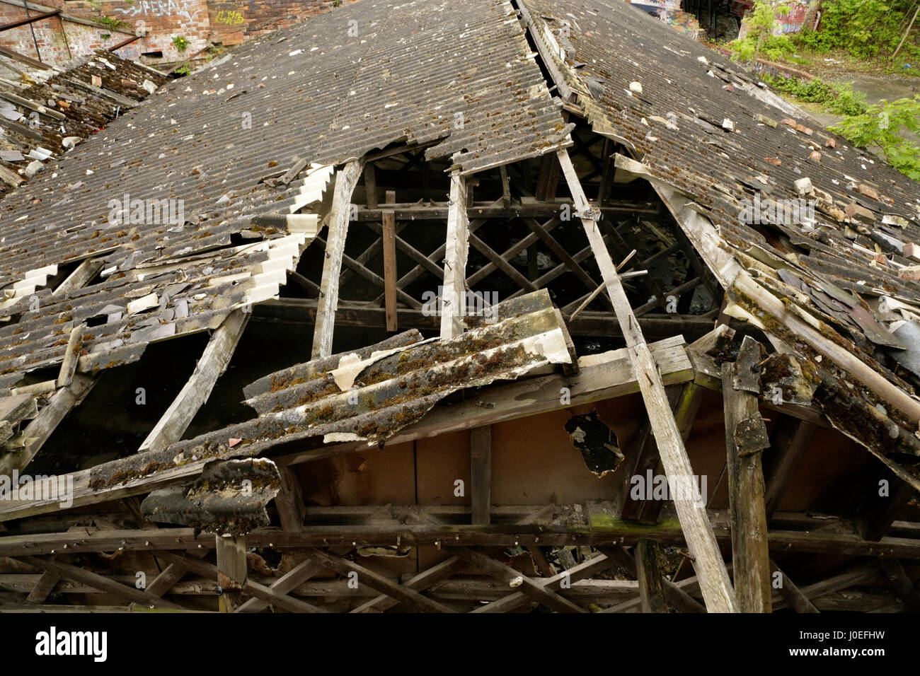 Danneggiato tetto in amianto corrugato sul vecchio stabilimento industriale abbandonato. Foto Stock