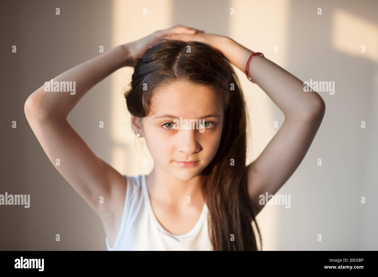 Adorabile ragazza facendo i suoi capelli con entrambe le mani Foto Stock