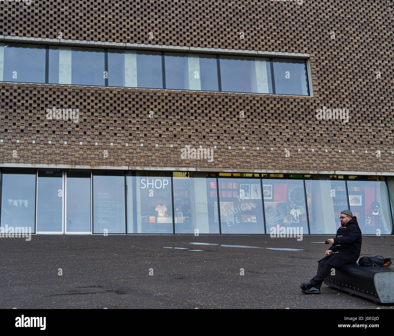 Uomo seduto al di fuori della Tate Modern di estensione, l'interruttore casa (da Herzog & de Meuron, South Bank di Londra, Inghilterra Foto Stock