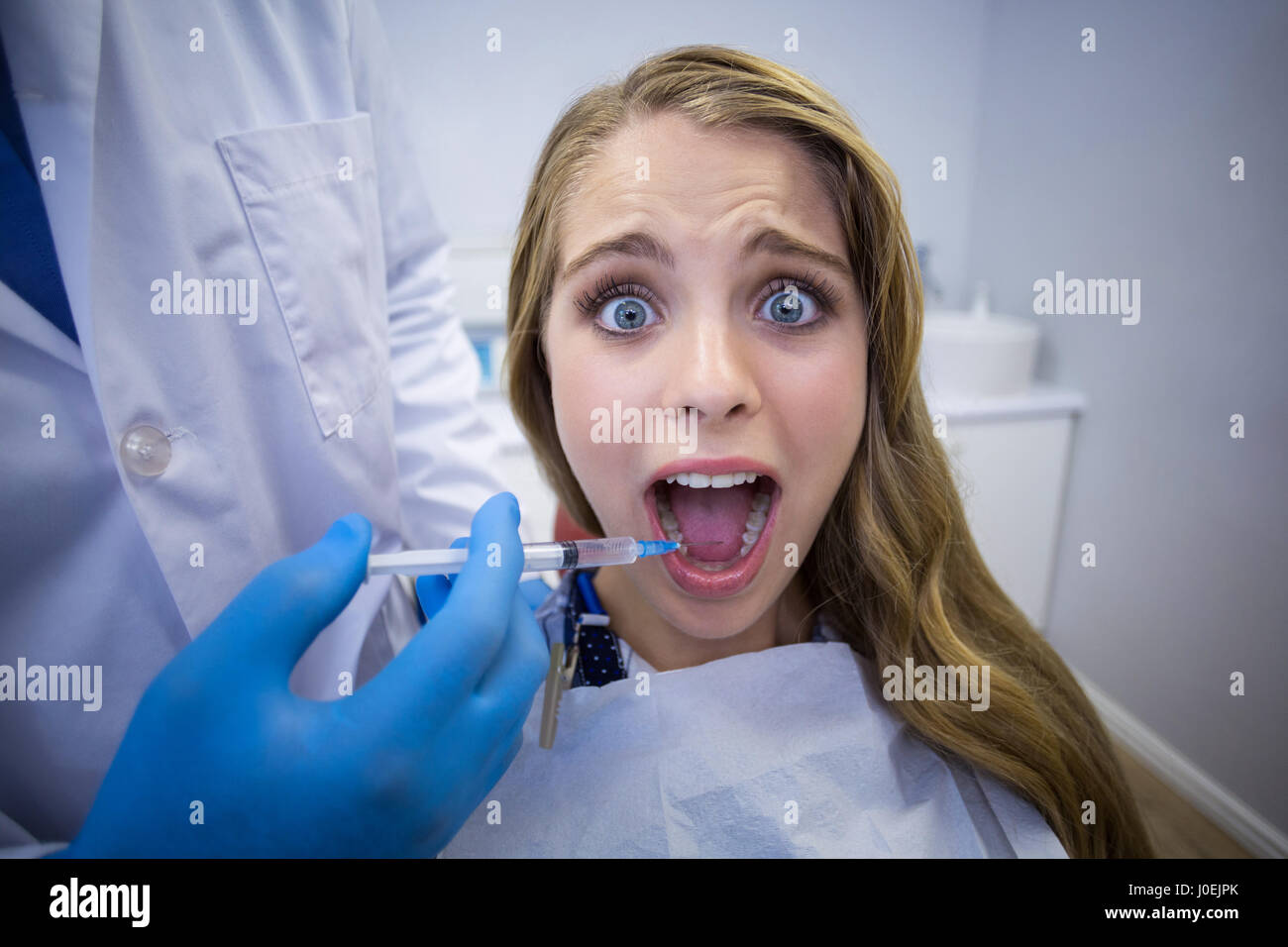 Dentista anestesia dando al paziente di sesso femminile in clinica Foto Stock