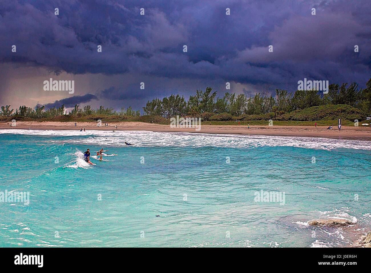 Surfers attendere onde come una tempesta si avvicina a un surf in spiaggia Jupiter, Florida. Foto Stock