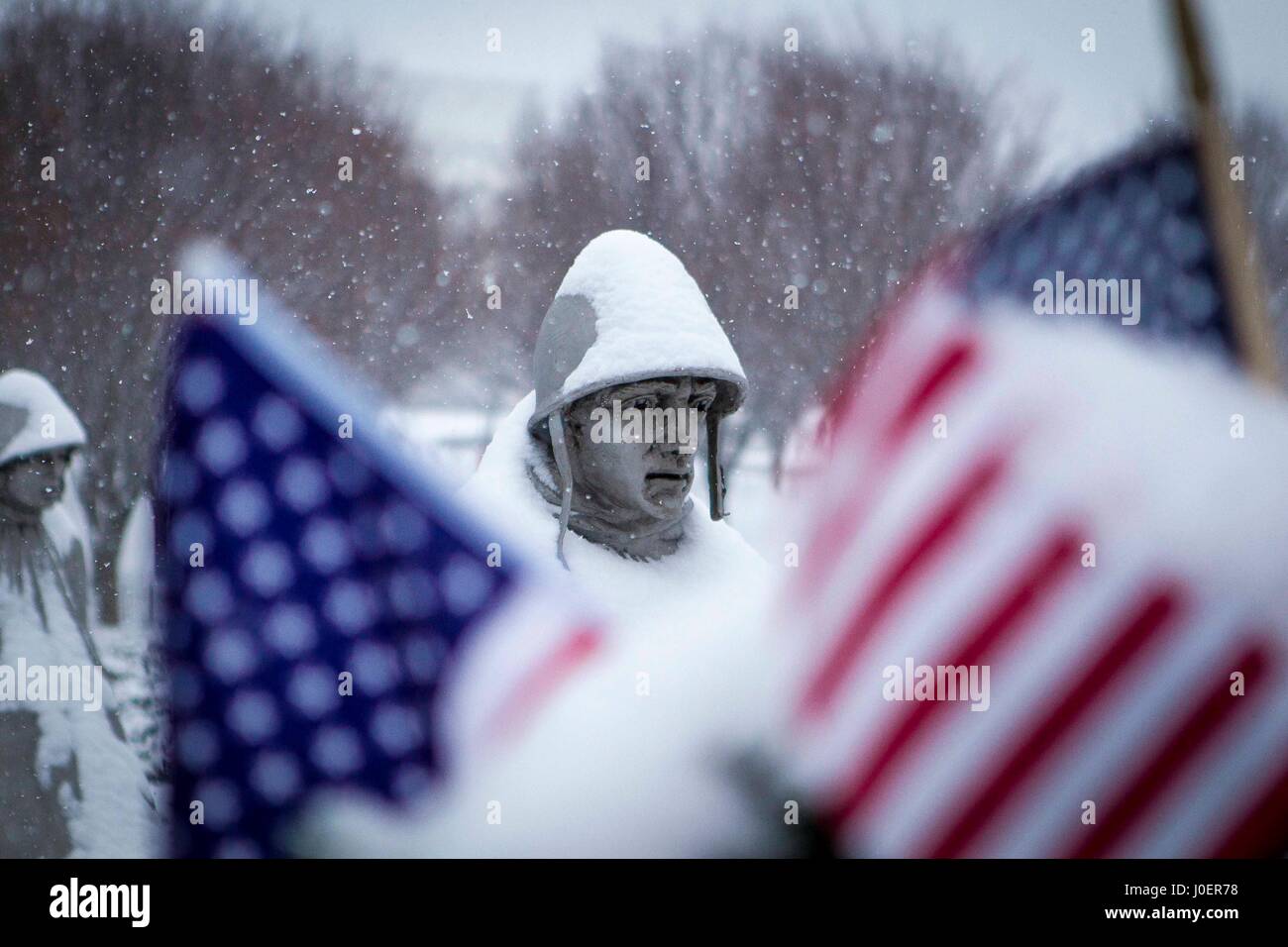 Una statua di una guerra di Corea soldato è incorniciata da due bandierine americane durante una tempesta di neve in coreano Memoriale di guerra sul National Mall di Washington, Foto Stock