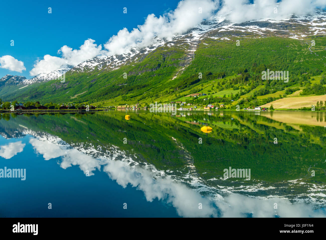 Lago perfetto riflesso di montagne innevate coperto di nuvole, Norvegia Foto Stock