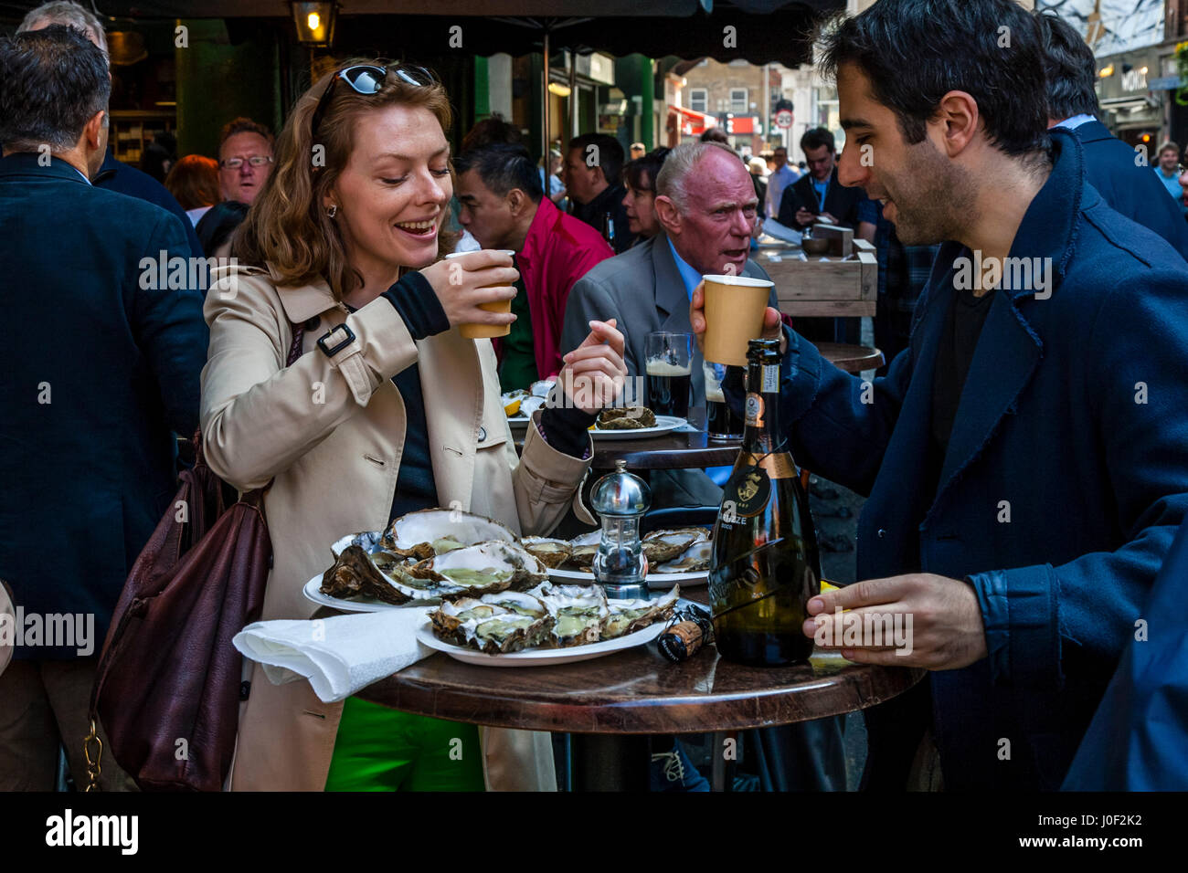 Due persone godendo di Prosecco e ostriche al di fuori di un ristorante nel mercato di Borough, Londra, Inghilterra Foto Stock