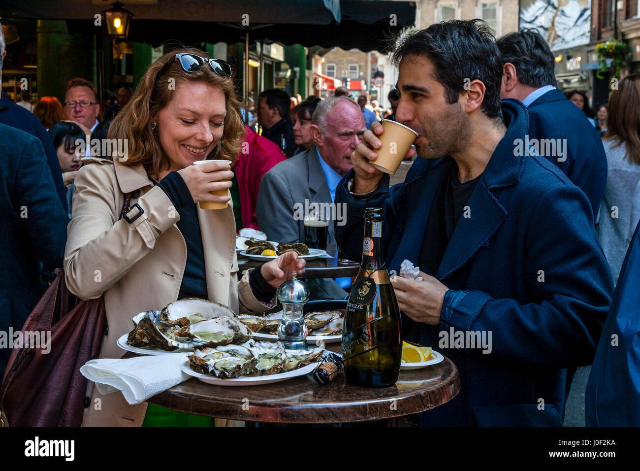 Due persone godendo di Prosecco e ostriche al di fuori di un ristorante nel mercato di Borough, Londra, Inghilterra Foto Stock