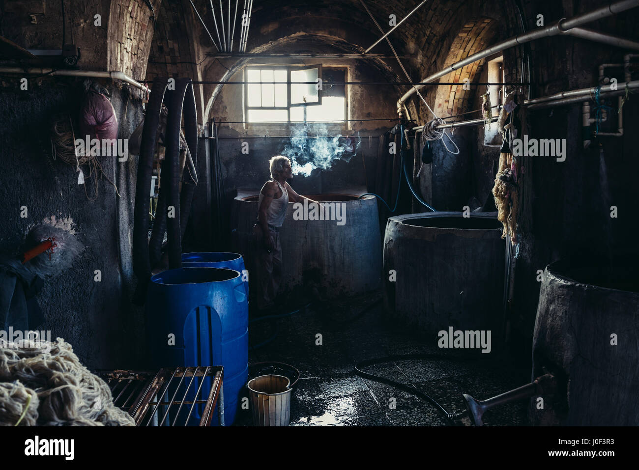 Lavoratore iraniano cigartette fumo in lana di piccola casa di colorante sul vecchio bazar di Kashan città, capitale della contea di Kashan in Iran Foto Stock