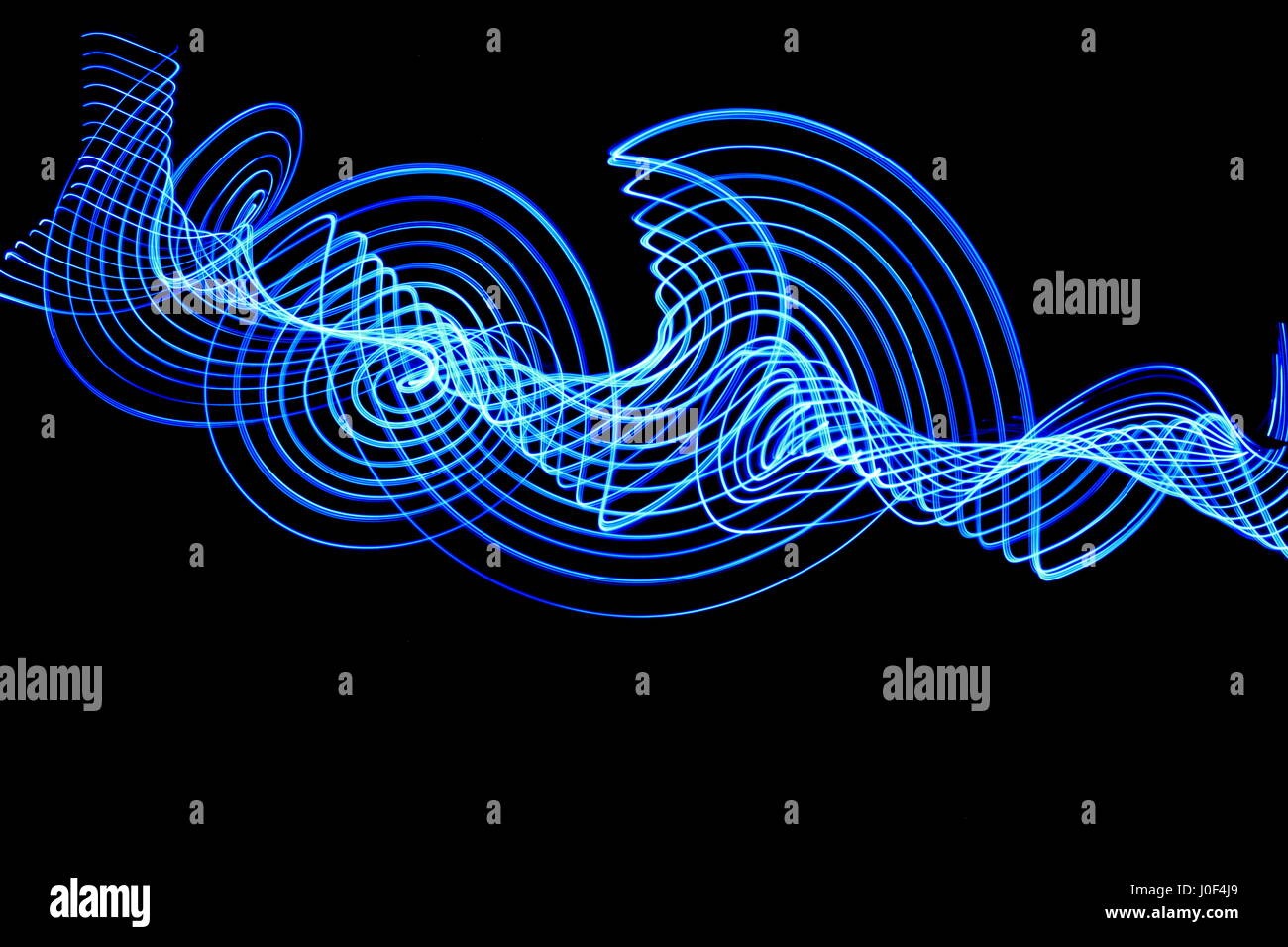 Una lunga esposizione fotografia di blu le luci fairy in un moto vorticoso pattern, luce fotografia pittura contro uno sfondo nero Foto Stock