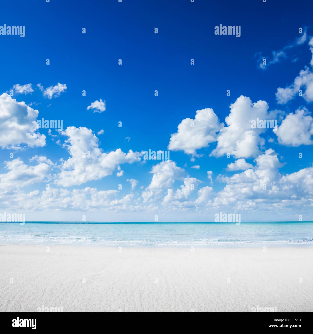 Spiaggia di sabbia bianca, oceano tropicale e blu cielo nuvoloso Foto Stock