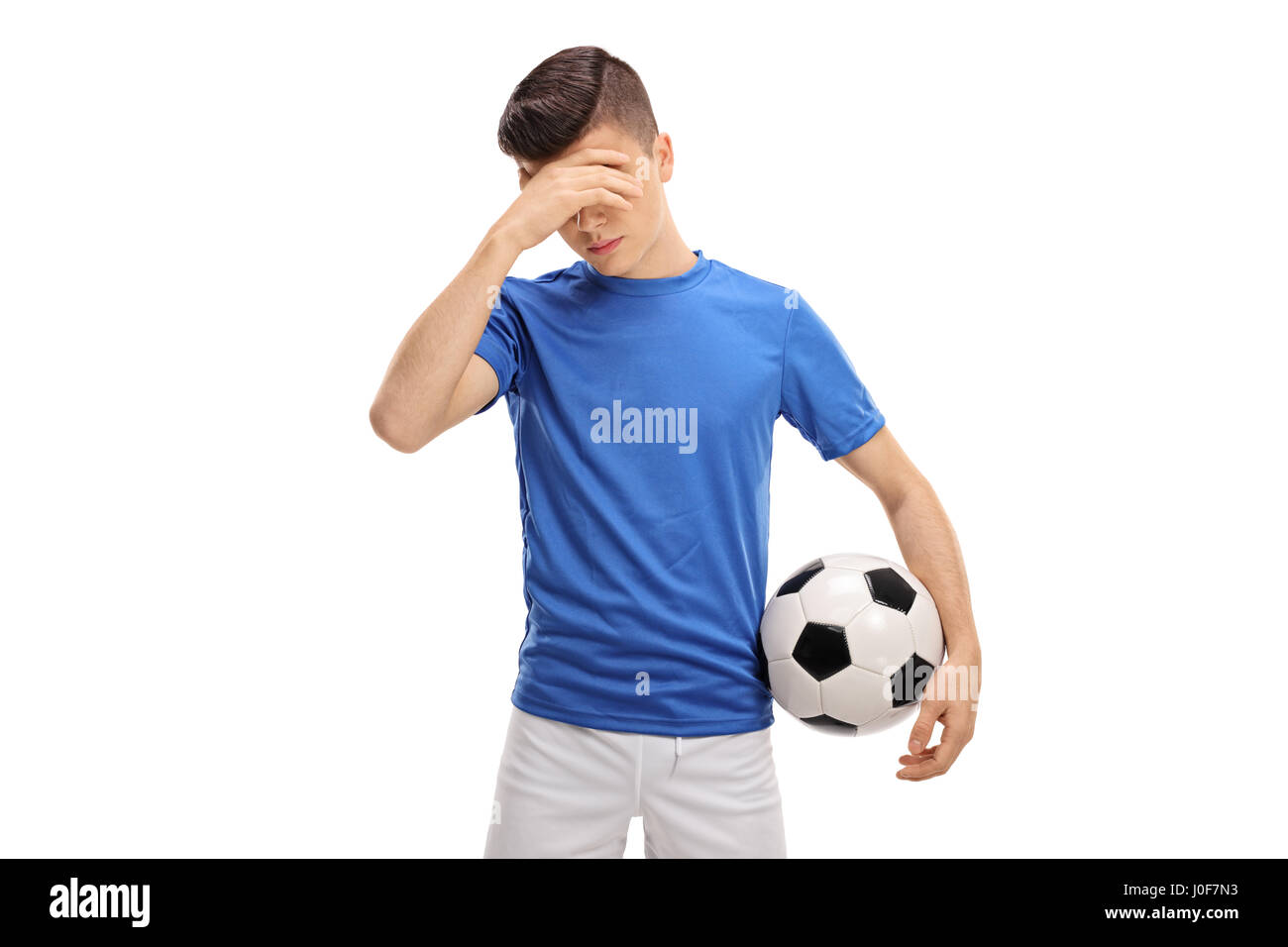 Sconvolto teenage giocatore di calcio tenendo la sua testa in incredulità isolati su sfondo bianco Foto Stock