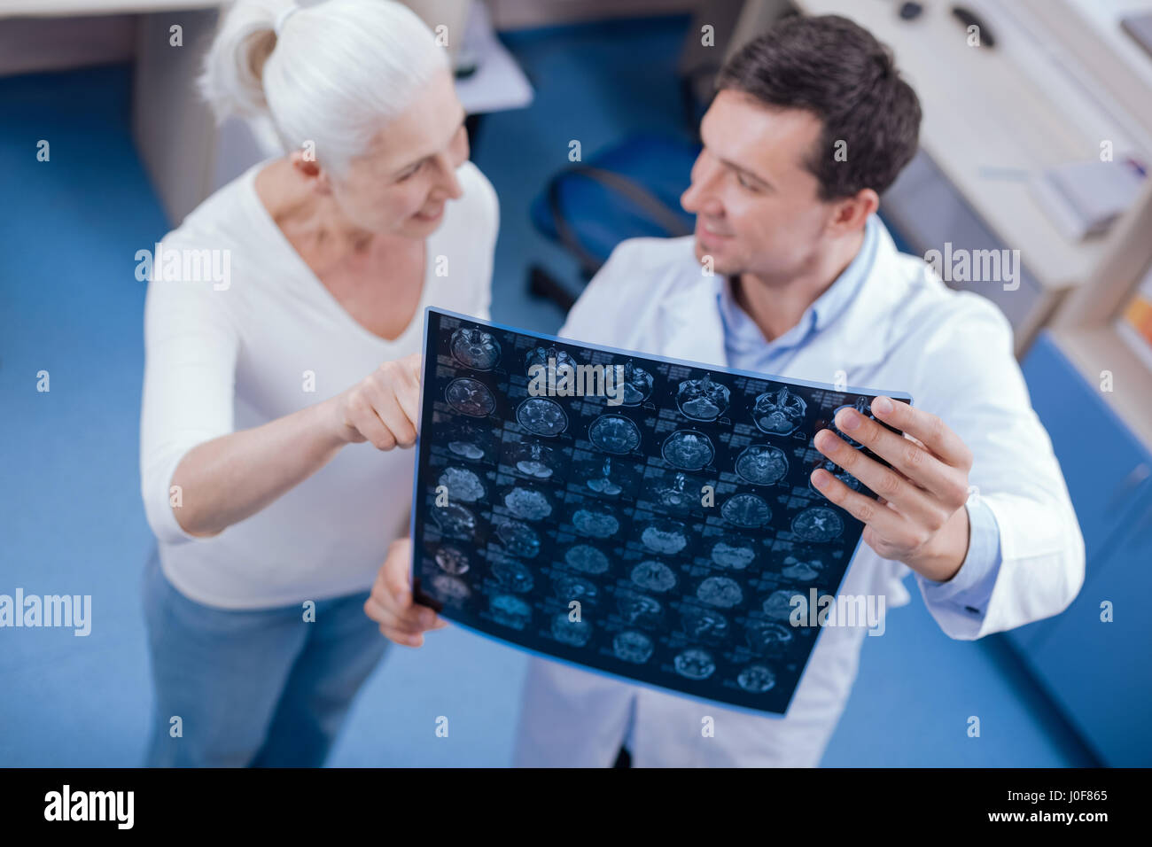 MRI scan. Messa a fuoco selettiva di immagini cerebrali essendo tenuto da un gioioso lieto allegro medico mentre interagiscono con il suo paziente Foto Stock