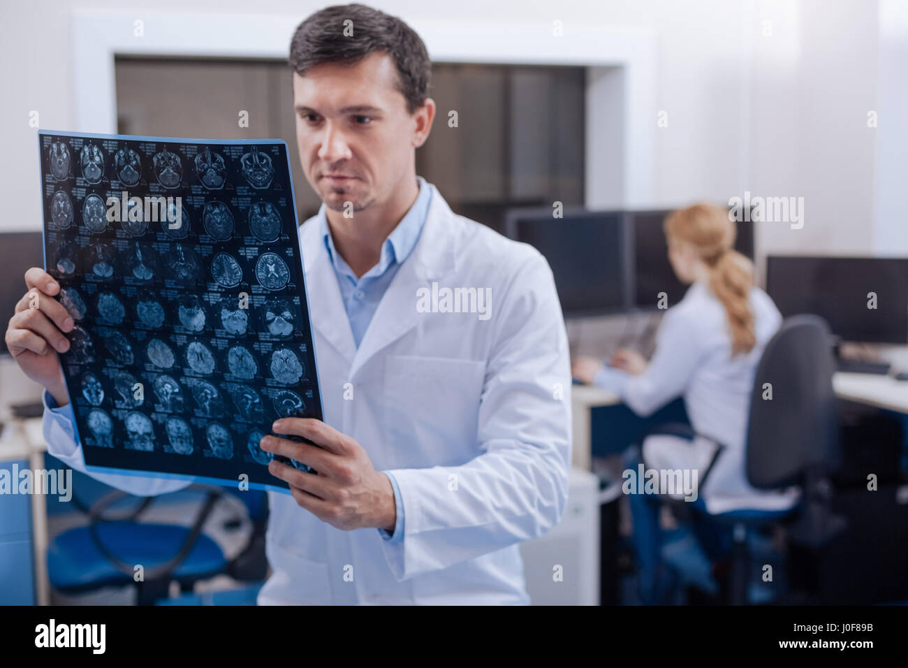 Studio diagnostico. Seria professionista medico maschio in piedi la staffroom ed esaminando la X ray immagini mentre si lavora nel dipartimento di oncologia Foto Stock