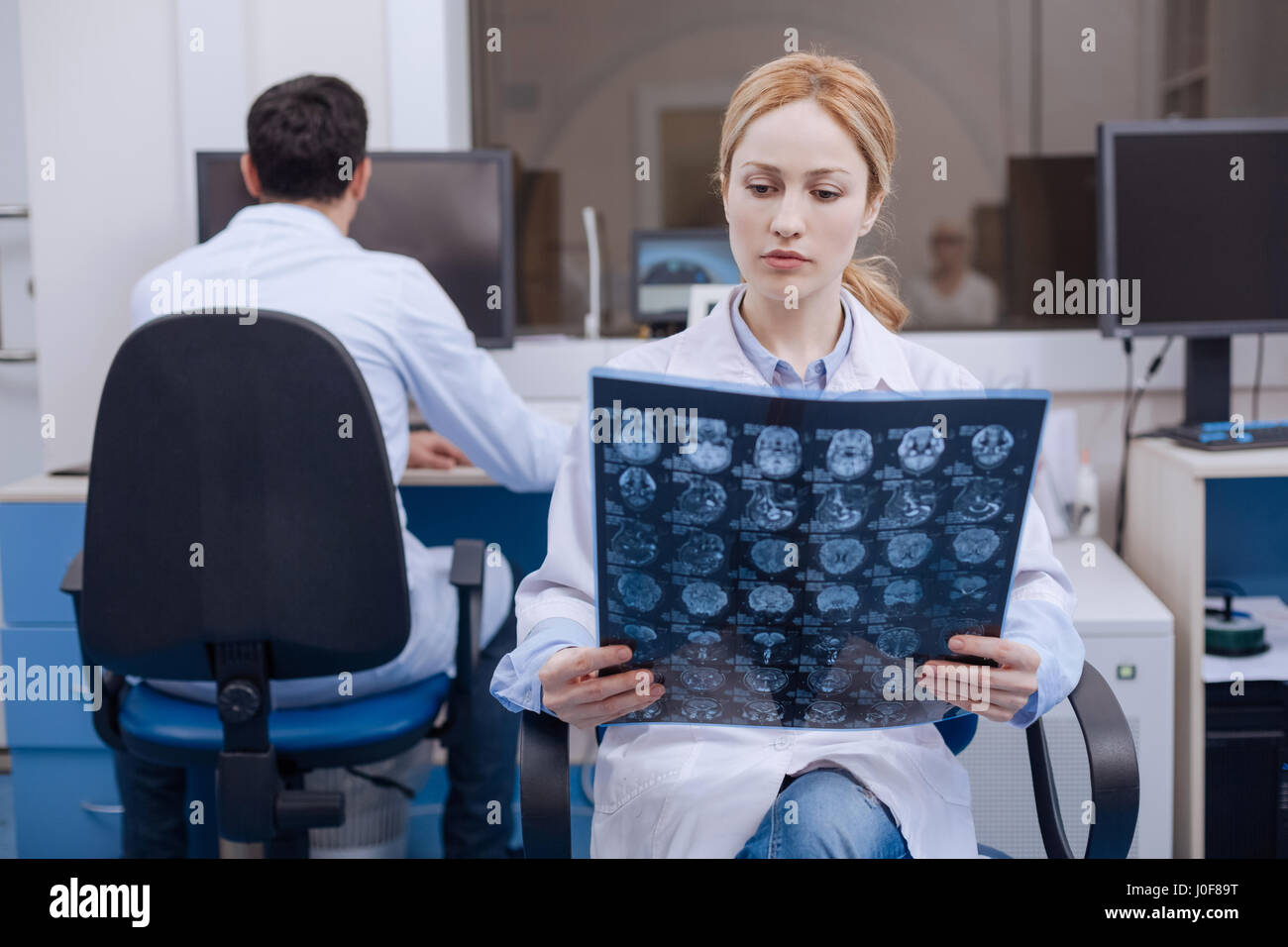 Dipartimento di Oncologia. Bella carino medico donna in possesso di un X ray immagine ed esaminando ponendo nel contempo una diagnosi Foto Stock