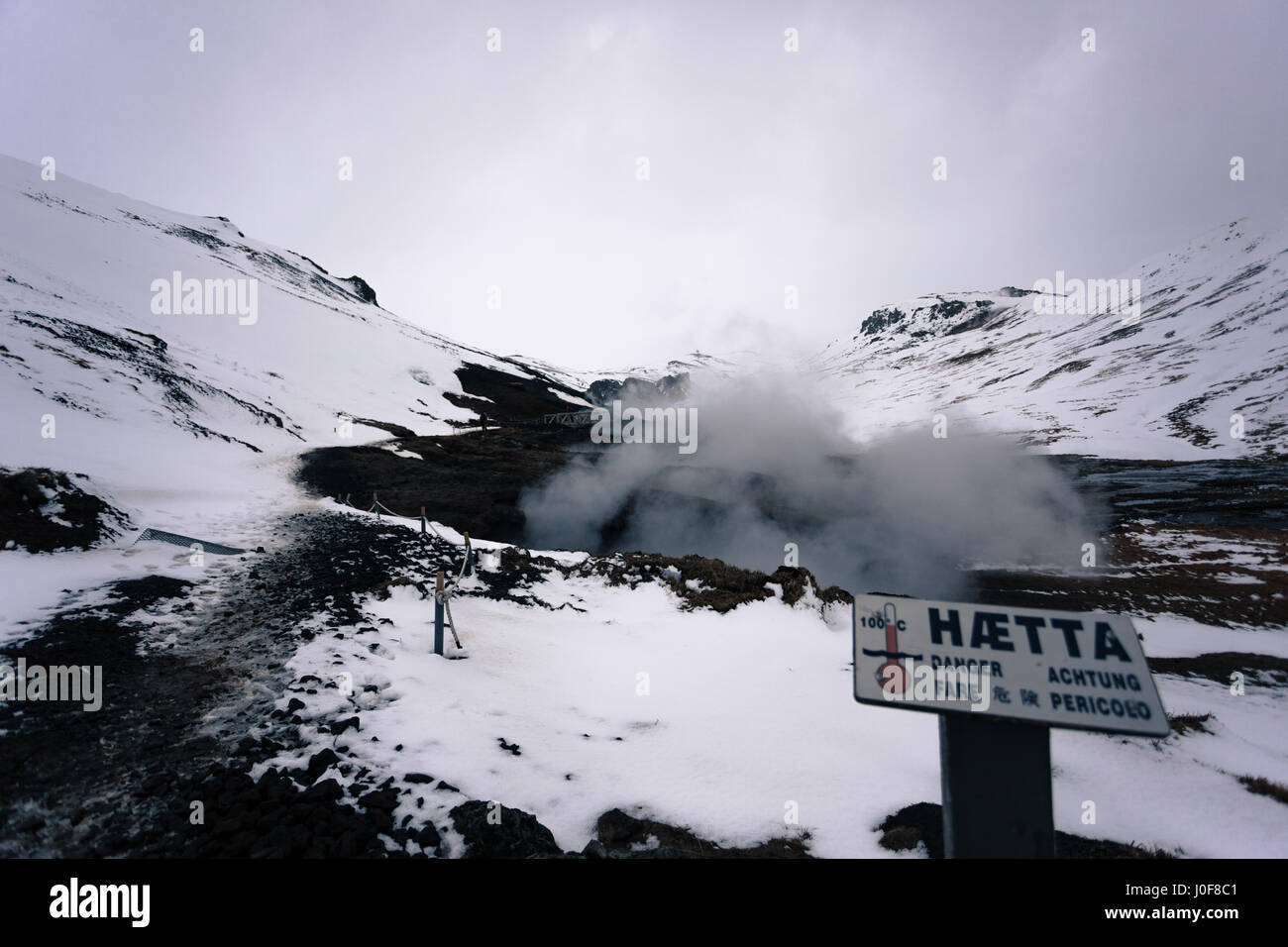Flutti di vapore vicino a un cartello di avviso da sorgenti calde geotermali di Reykjadalur, un famoso sentiero escursionistico nelle montagne vicino a Reykjavik, Islanda Foto Stock