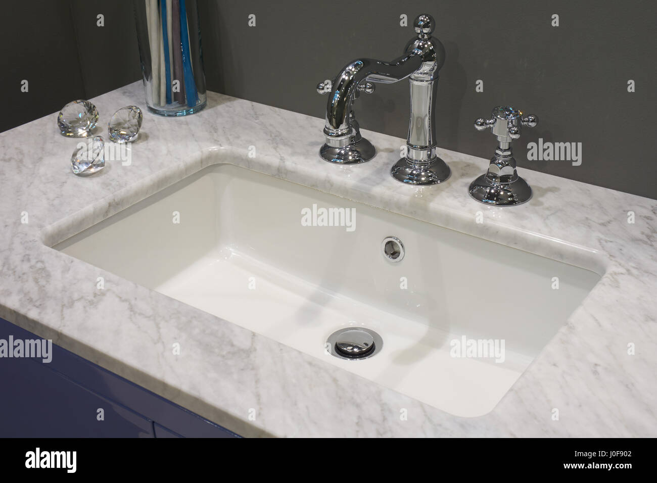 Il riquadro bianco lavabo in ceramica con metallo lucido miscelatore e tavola di marmo Foto Stock
